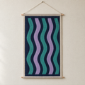 Aurora screen-printed canvas wall hanging on beech dowels, hung on a plain wall