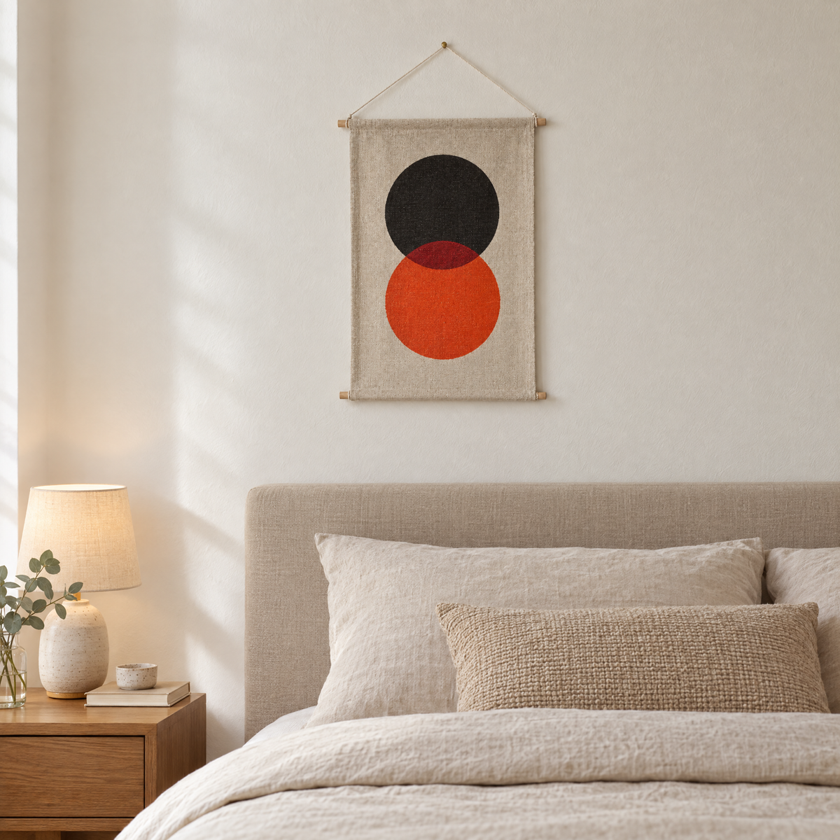 Eclipse wall hanging above a bed with oatmeal linen