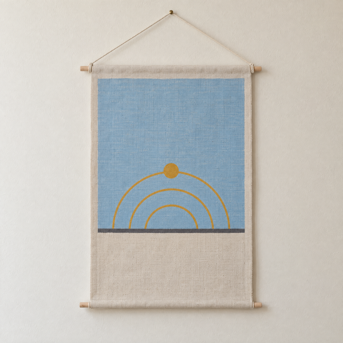 Sun Path screen-printed canvas wall hanging on beech dowels, hung on a plain wall