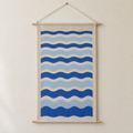 Tide Lines screen-printed canvas wall hanging on beech dowels, hung on a plain wall